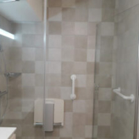 salle de bain pour personnes âgées équipés d'un siège de douche et de barre de maintien